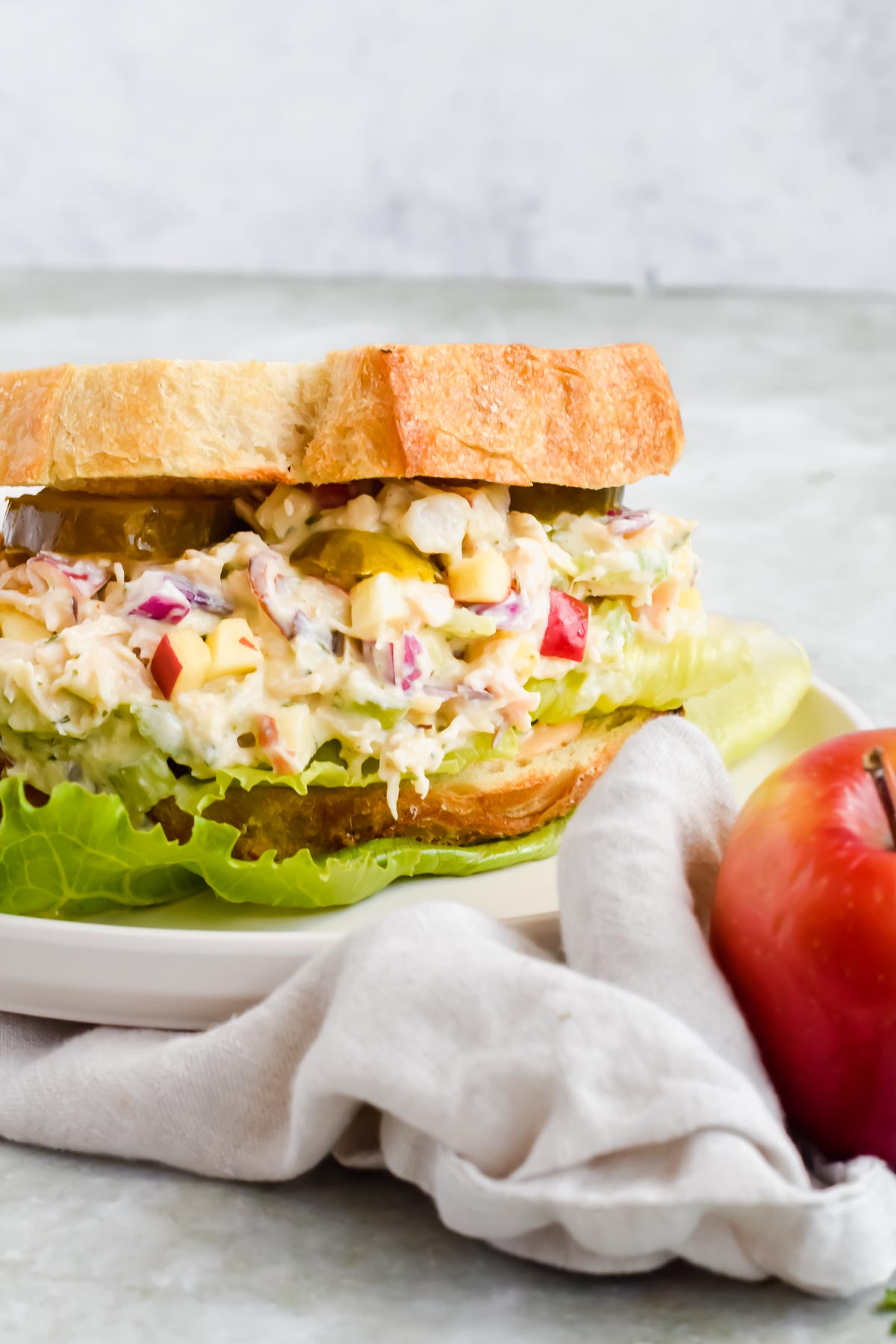 healthy pesto chicken salad between two slices of toasted bread on white plate.
