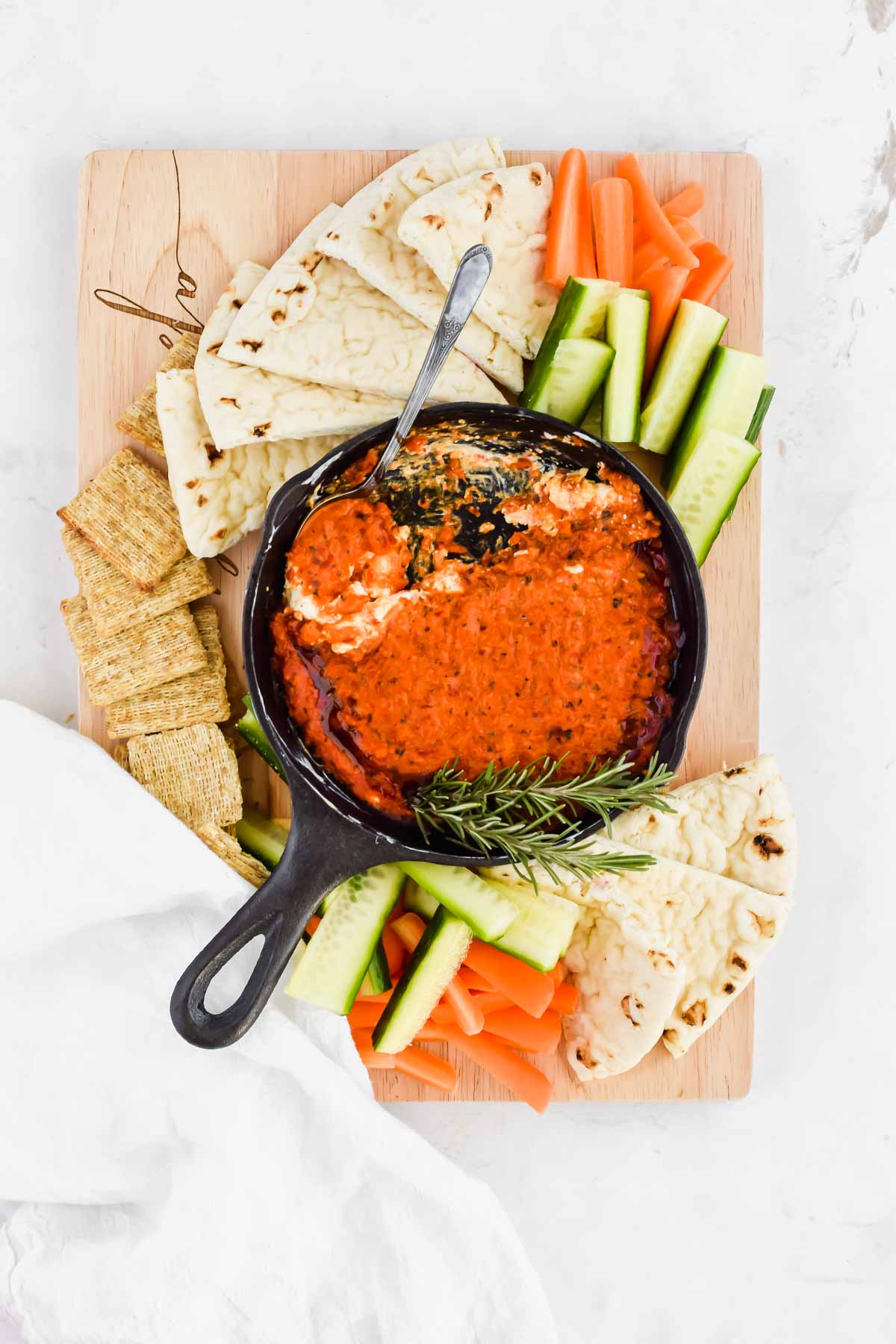 romesco dip in a cast iron skillet served with crackers, pita bread, and fresh vegetables.