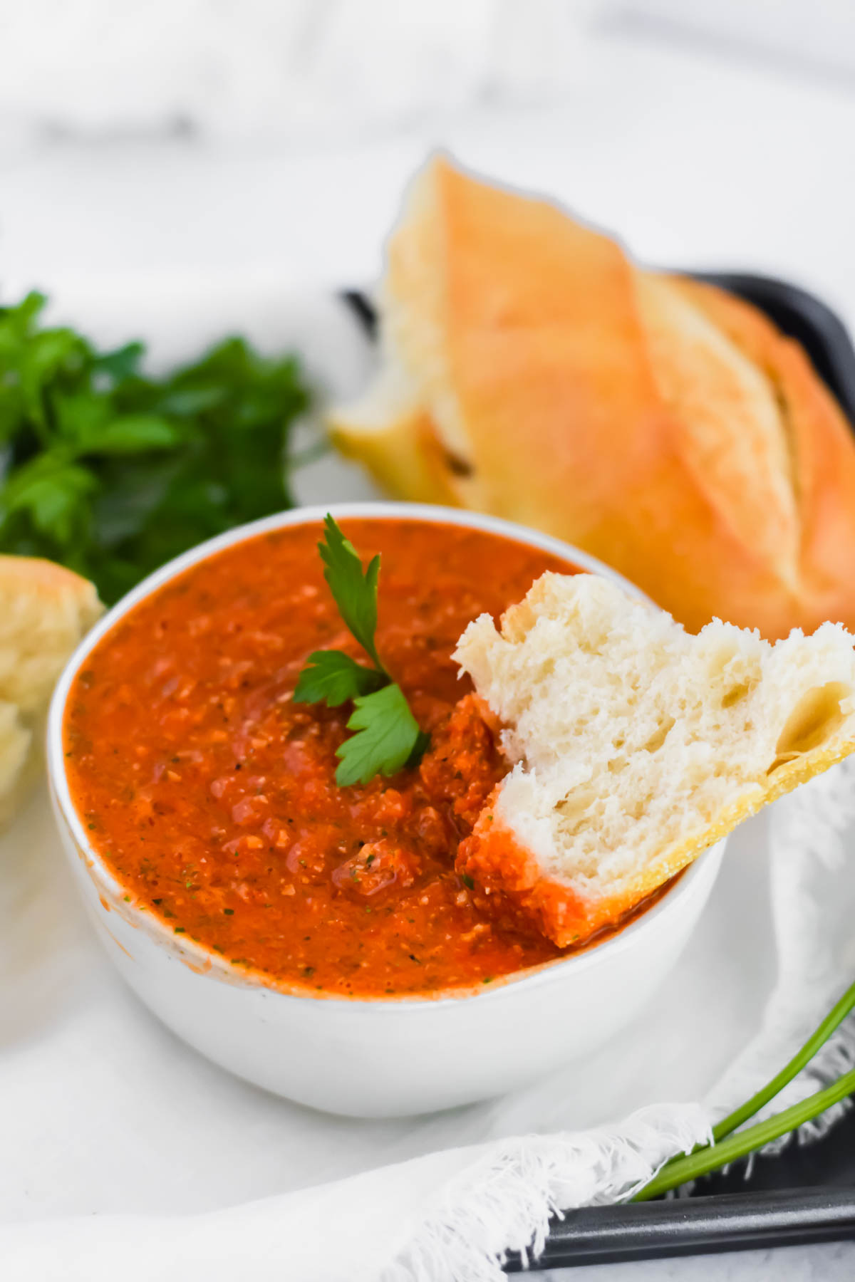 close up image of romesco dip bowl with piece of bread dunked into it.