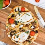 Savory Breakfast Flatbread with hummus, fried eggs, vegetables, goat cheese and balsamic glaze.