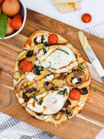 Savory Breakfast Flatbread with hummus, fried eggs, vegetables, goat cheese and balsamic glaze.
