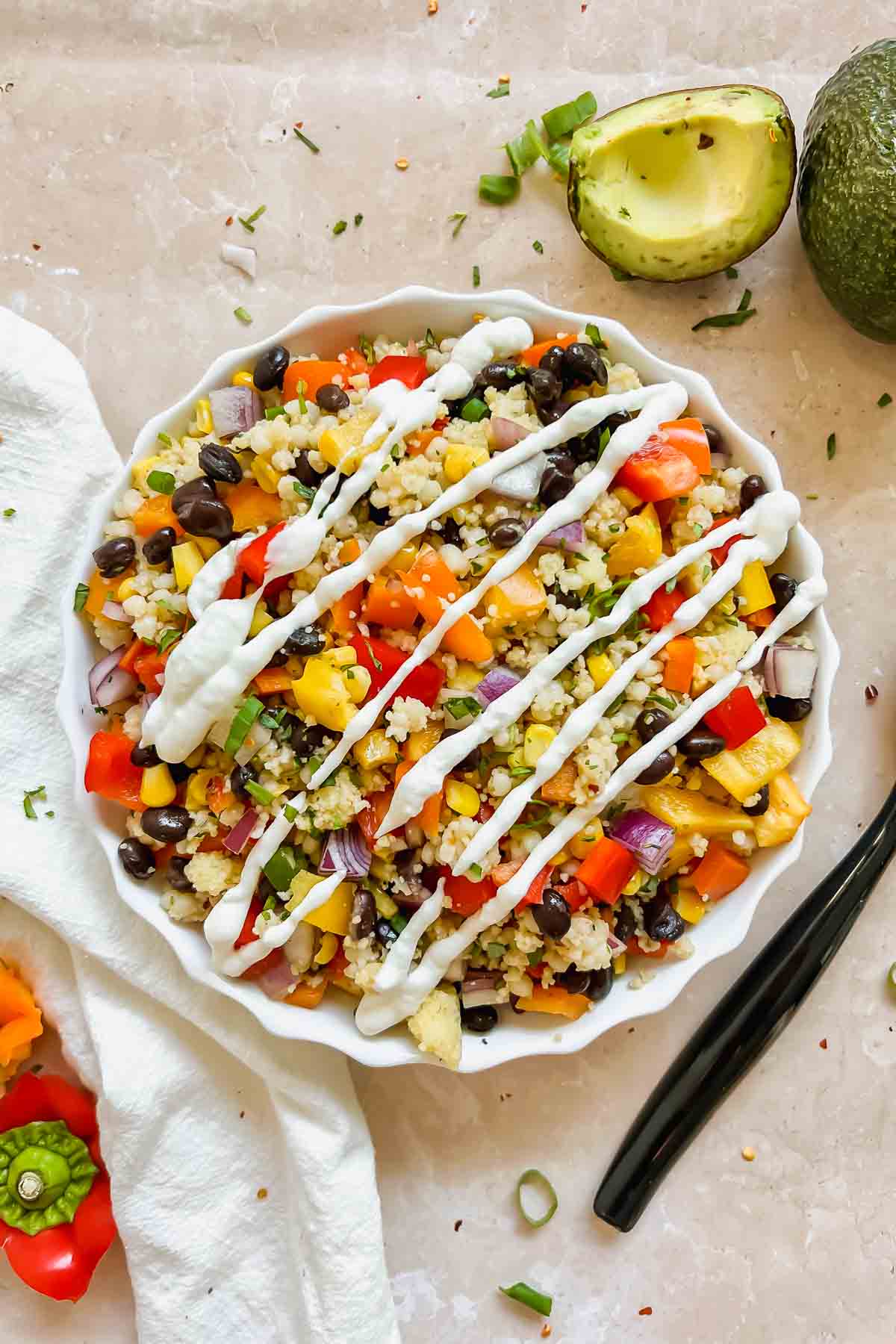 black bean couscous salad topped with fresh mexican crema in a white ceramic bowl.