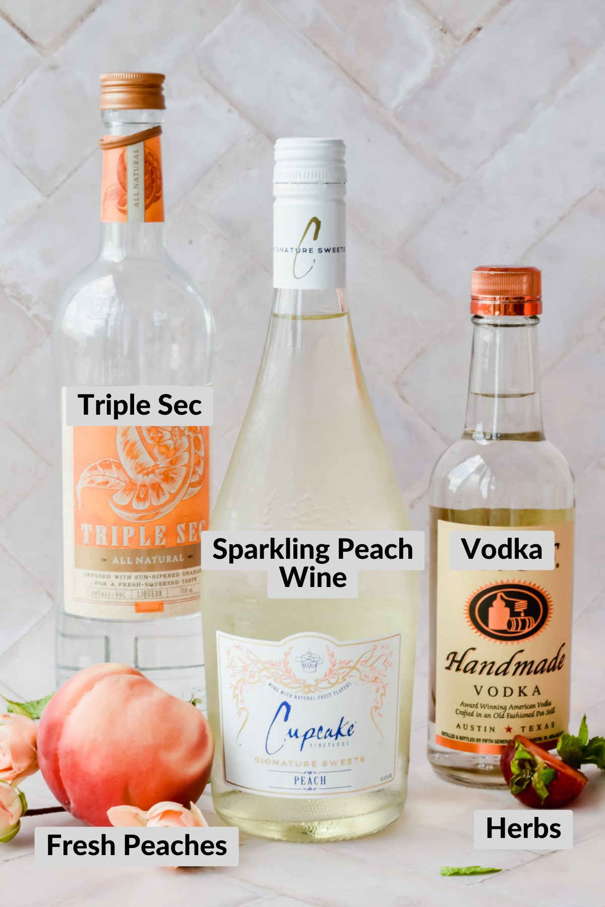 ingredients needed for this recipe: bottles of white wine, vodka, triple sec, and fresh fruit on a pink background.
