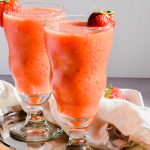 two frozen strawberry mango daiquiri cocktails in glasses garnished with a fresh strawberry.