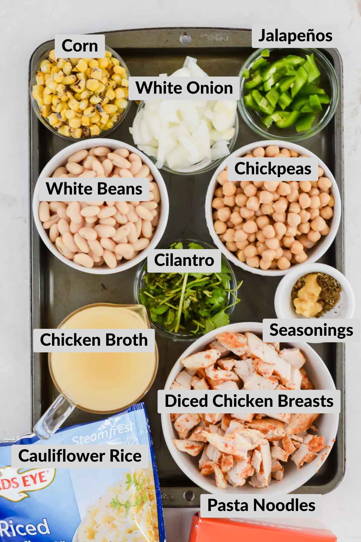 Ingredients for Dairy Free White Chicken Chili Recipe in individual bowls on gray baking sheet.