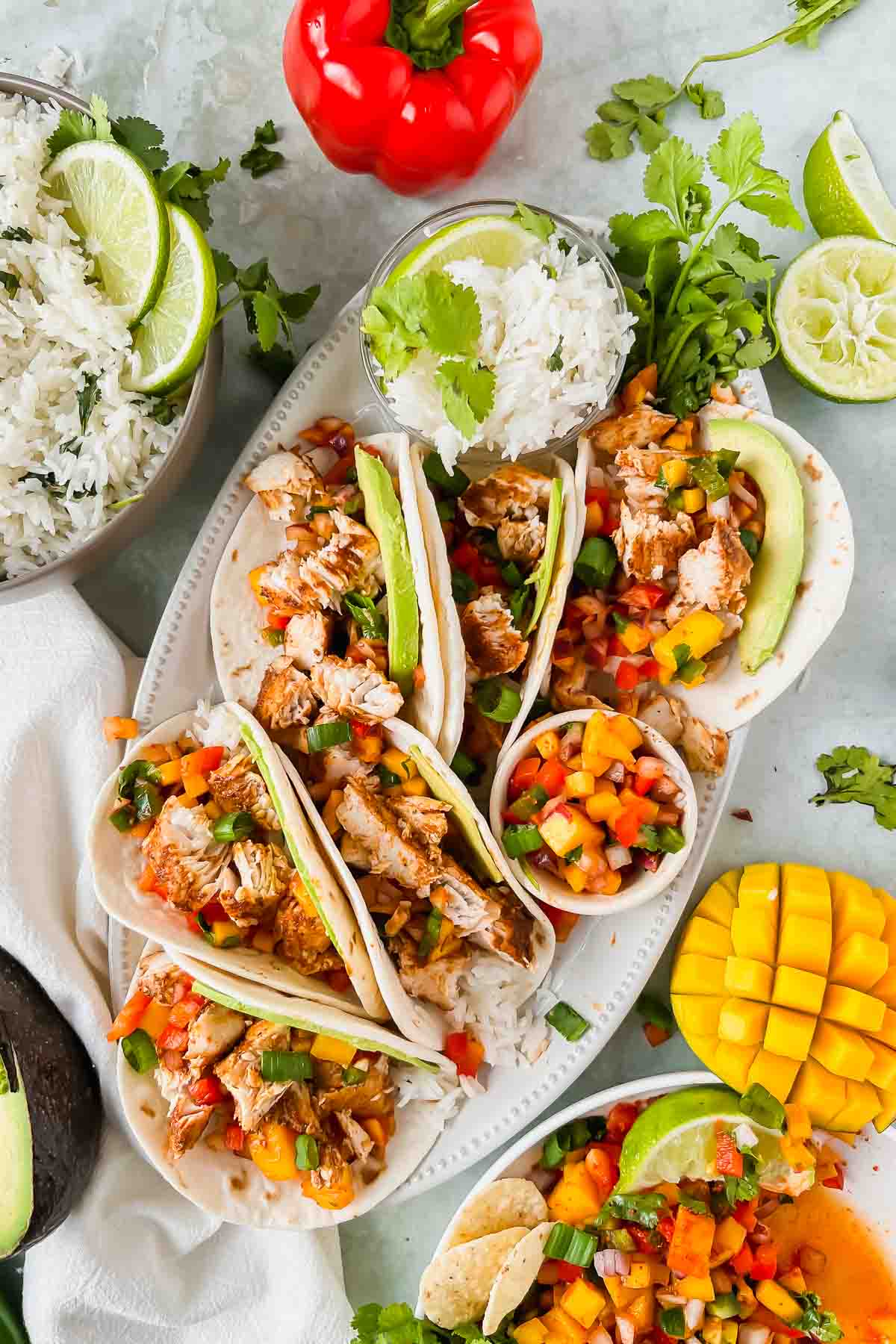 6 blackened mahi tacos on white serving plate surrounded by taco toppings.