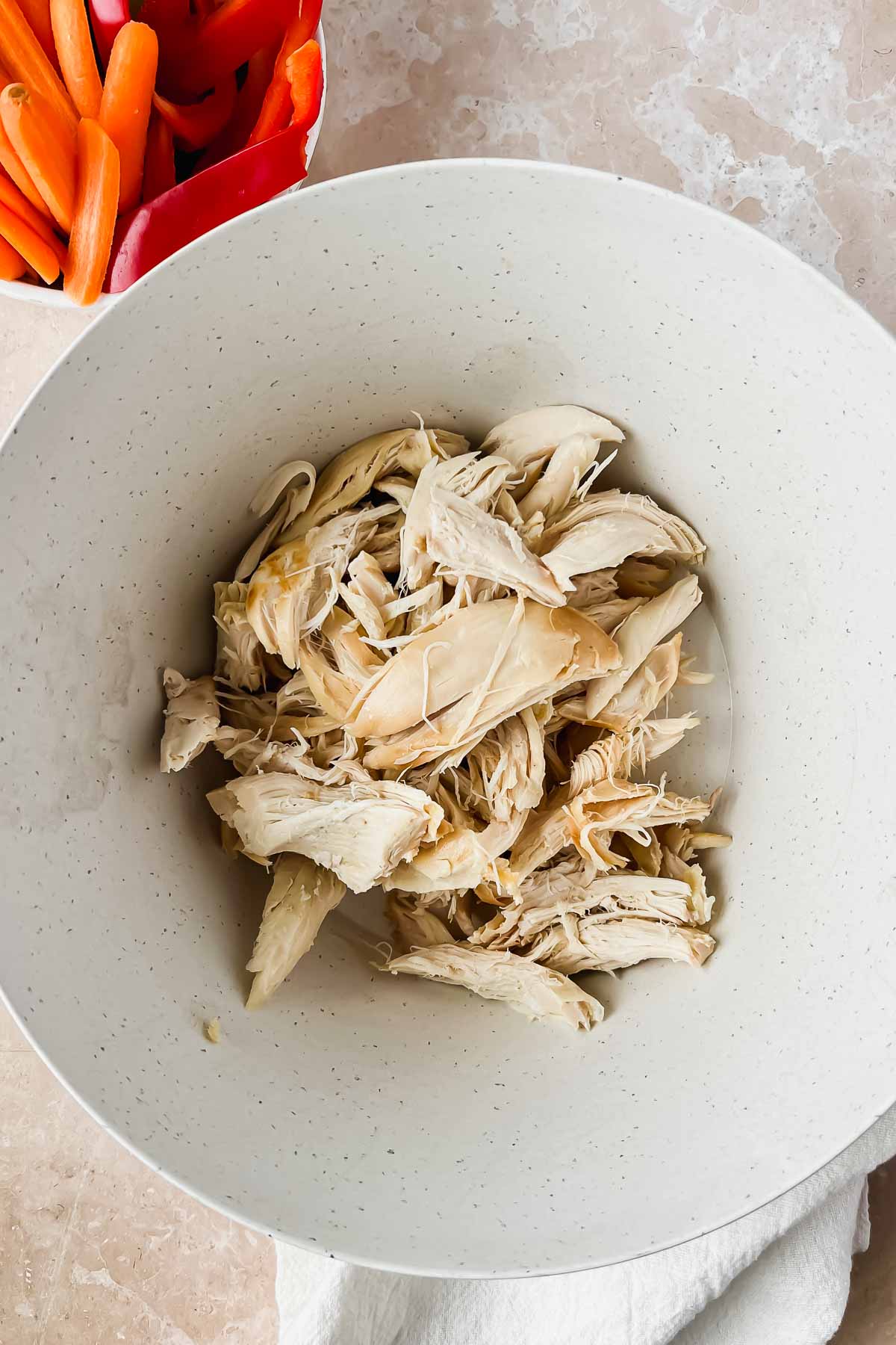 Shredded chicken in a metal mixing bowl.