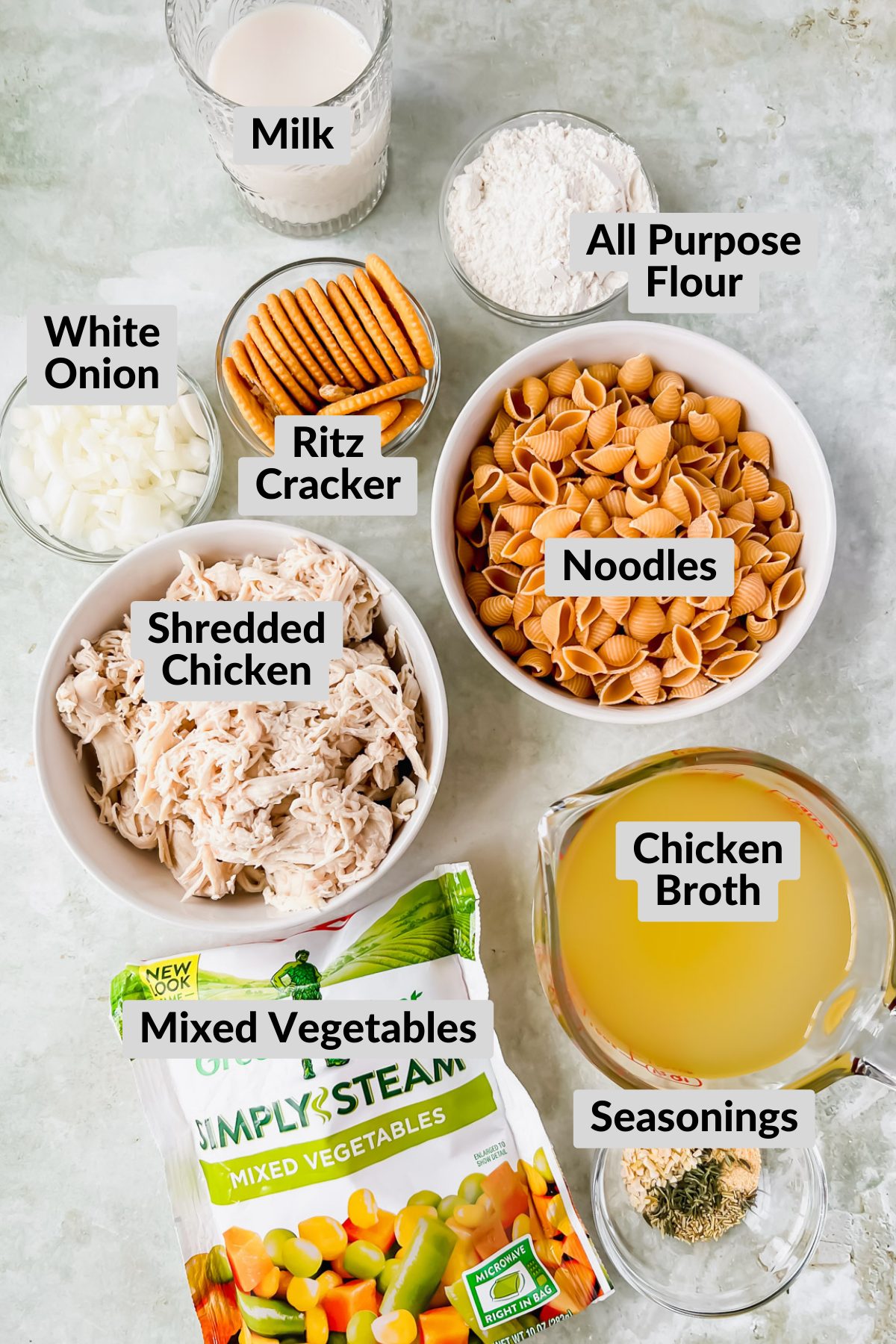ingredients for chicken noodle soup casserole in individual bowls on stone background.
