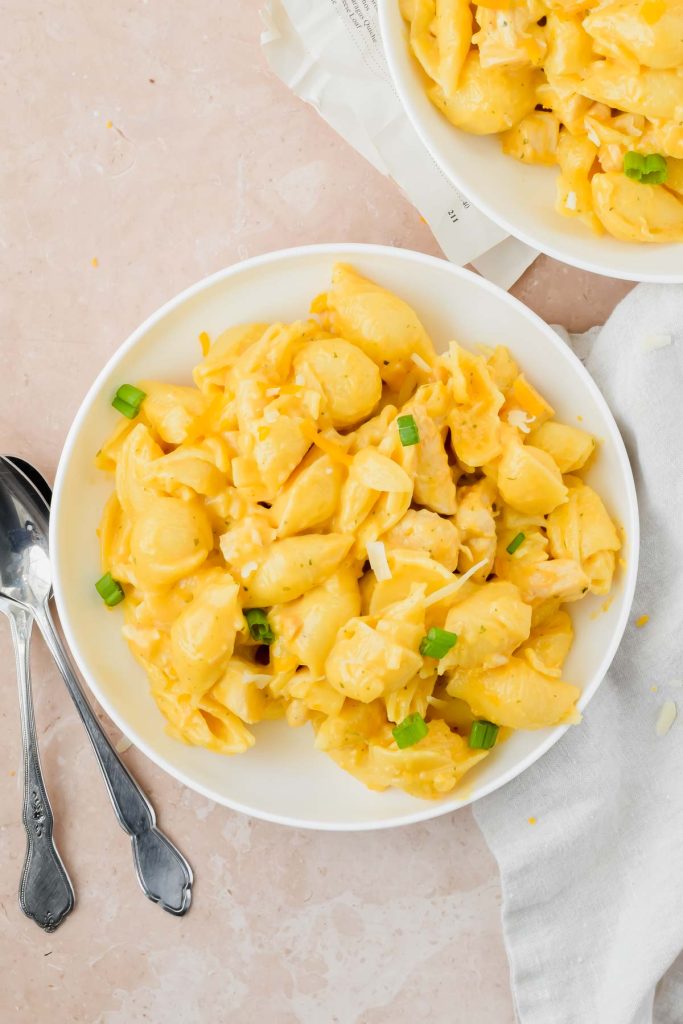 white bowl filled with chicken ranch mac n cheese with a silver spoon on a stone background.