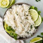 chipotle cilantro lime rice garnished with fresh limes in a grey bowl on green backdrop.