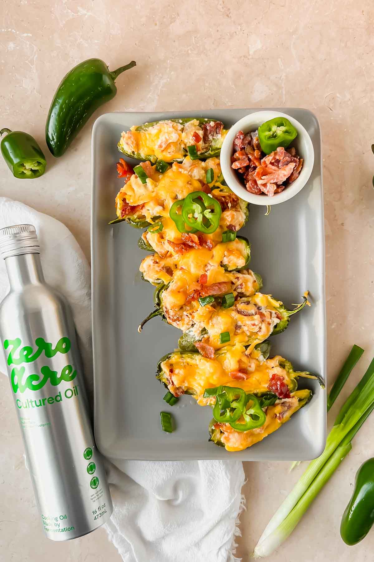 baked jalapeño shrimp poppers topped with shredded cheese arranged in a line on gray serving plate.