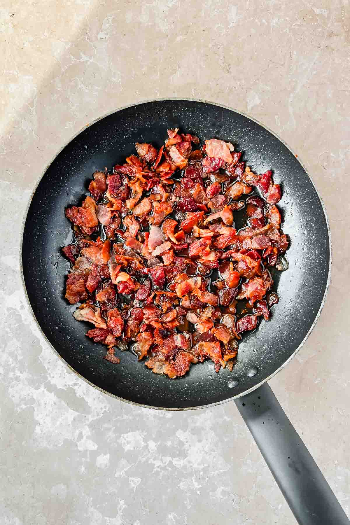 cooked bacon bits in black skillet.