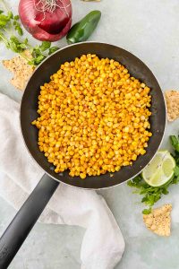 skillet filled with corn on green background and white linen.