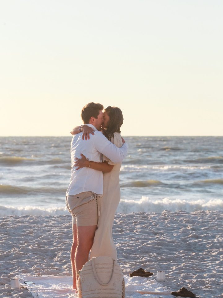 man and woman standing on a beach a sunset hugging.