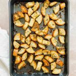 metal sheet pan with cooked french bread croutons on stone background.