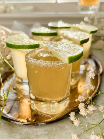 6 green tea shots topped with lime wedge on silver platter.