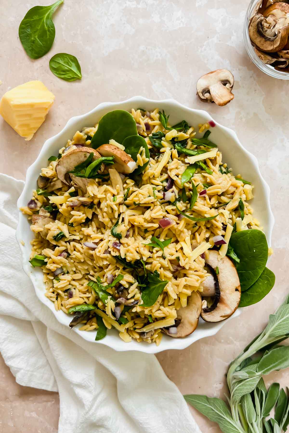 mushroom rice pilaf garnished with fresh mushrooms and spinach in white ceramic bowl on stone background.