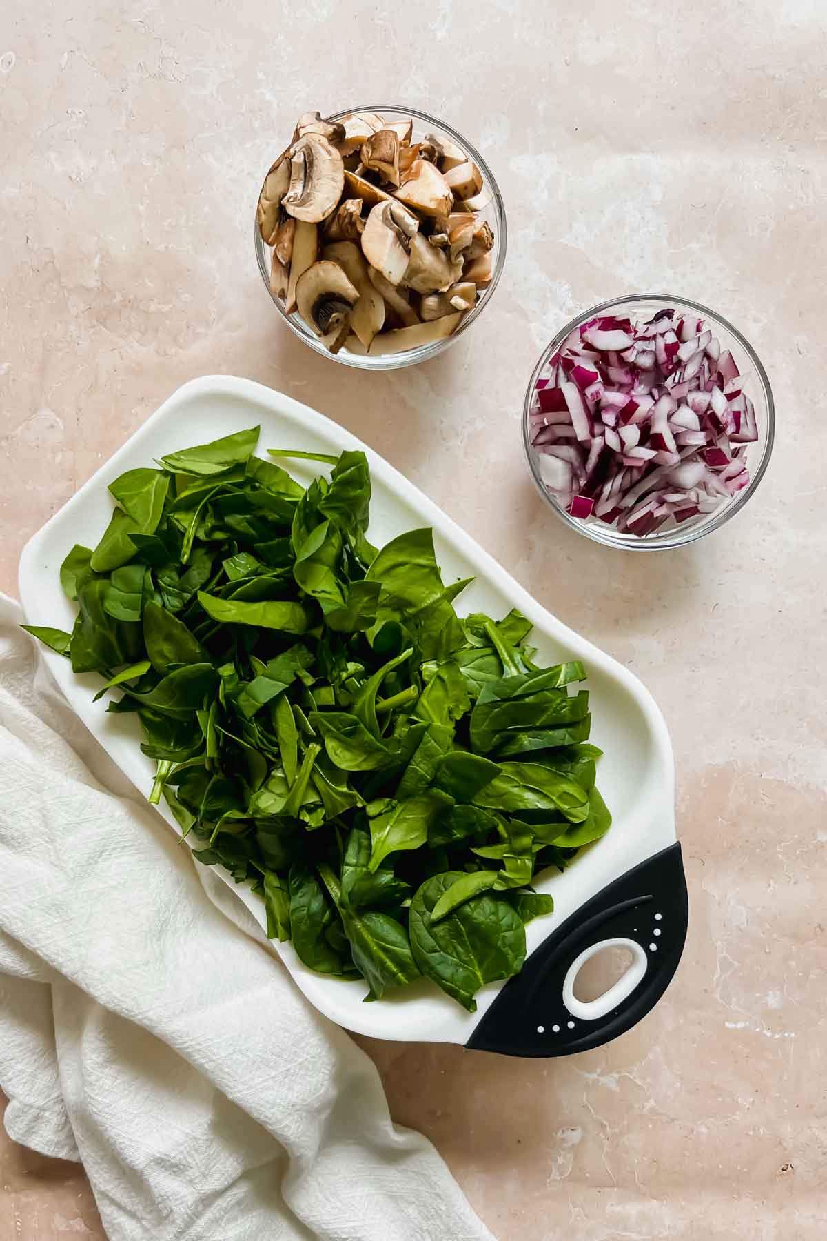 diced spinach, mushroom, and onion on stone background.