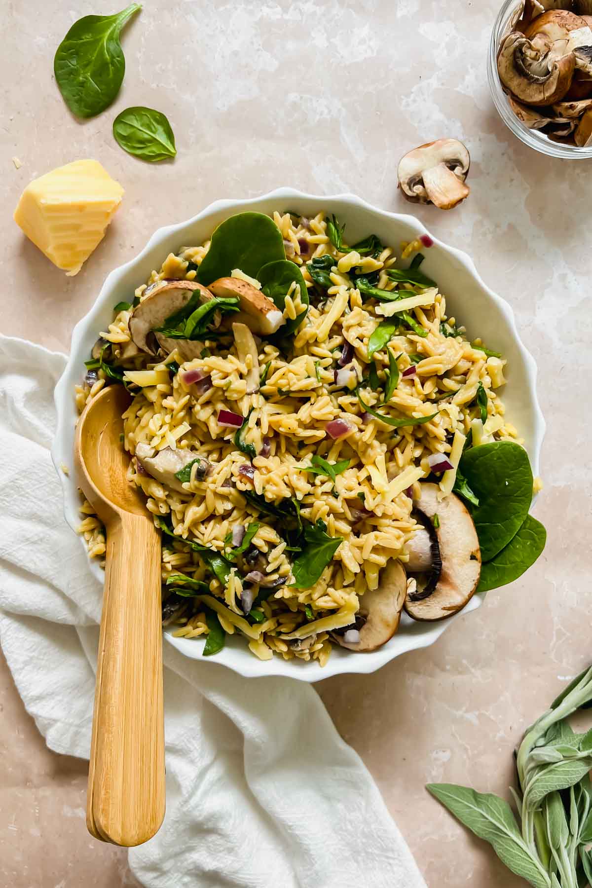 cooked mushroom rice pilaf garnished with fresh spinach and mushrooms with wooden spoon on stone background.