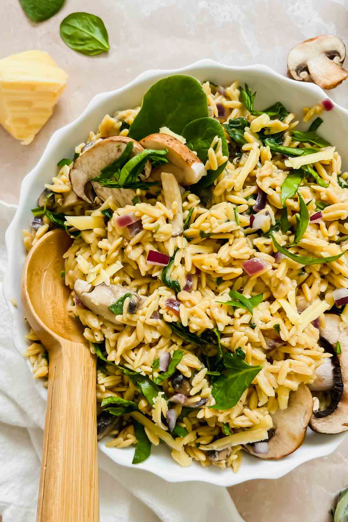 wooden spoon serving cooked cheesy mushroom rice pilaf in white ceramic bowl. 