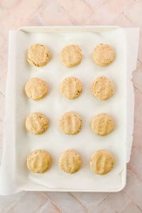 12 raw oat flour biscuits on parchment lined baking sheet.