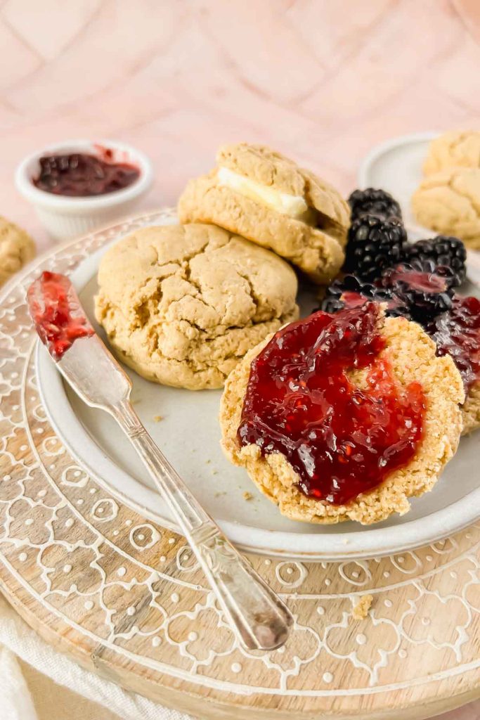 white plate of oat flour biscuits spread with raspberry jam.