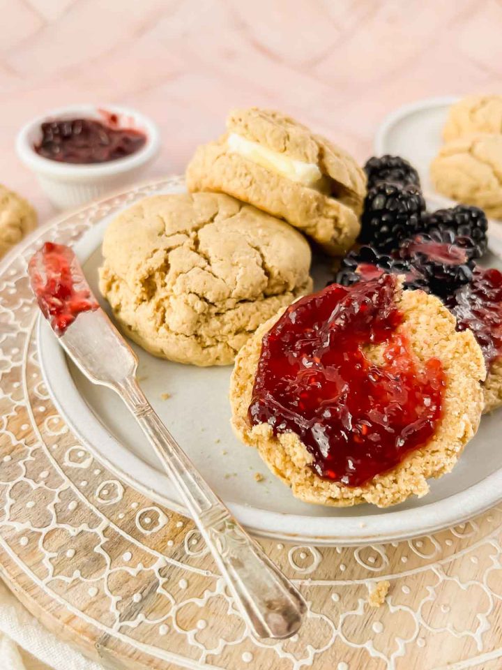 white plate of oat flour biscuits spread with raspberry jam.