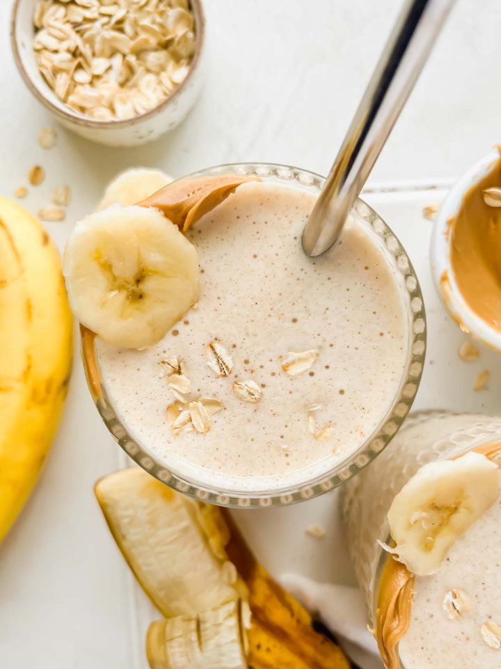 banana bread protein smoothie garnished with banana slice, peanut butter and rolled oats.