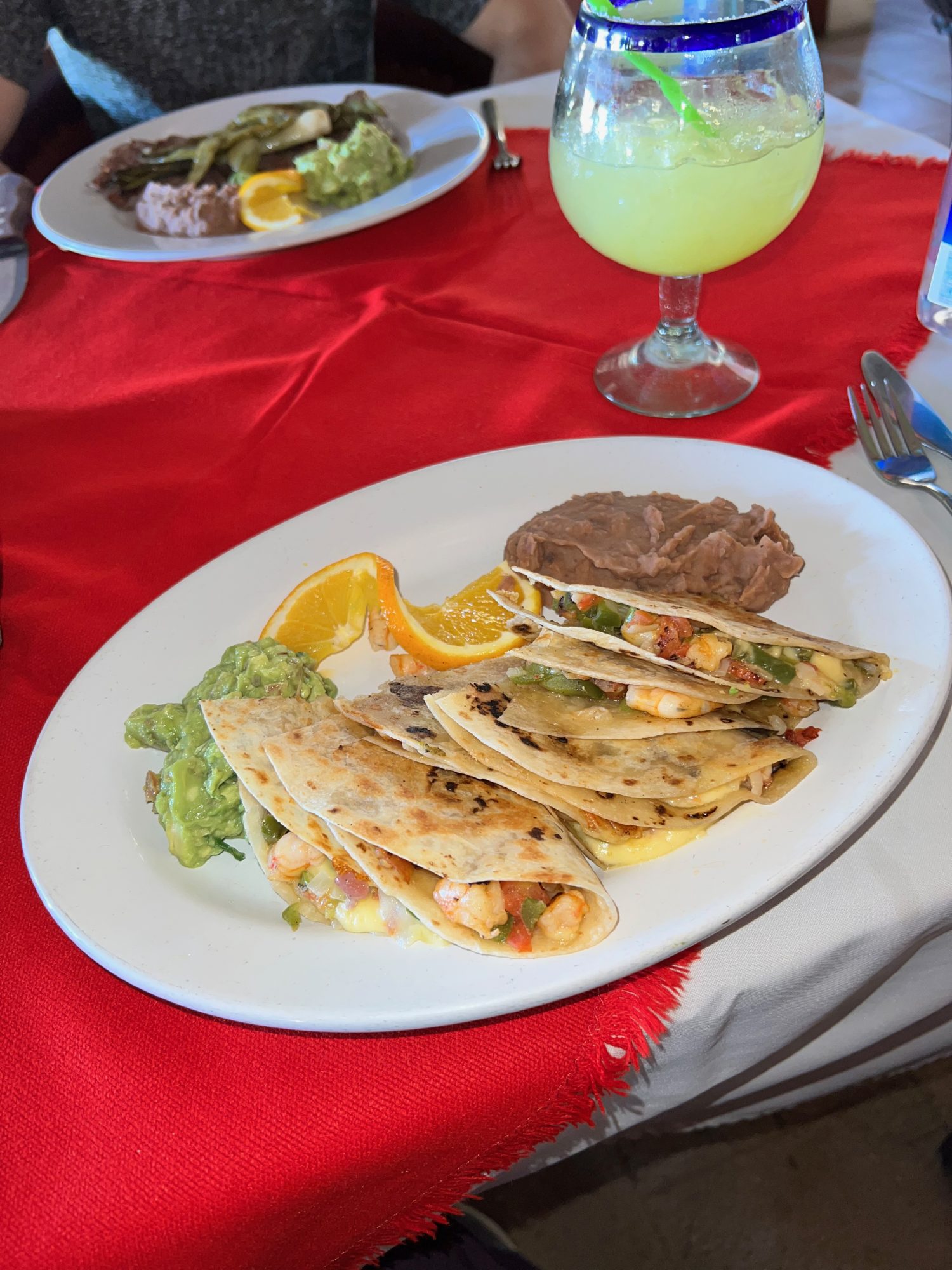 authentic shrimp quesadillas in San Jose del Cabo on a white plate with red tablecloth. 