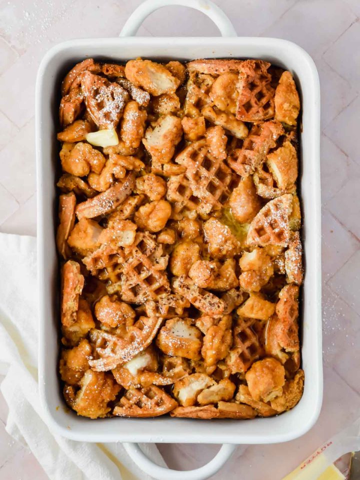 chicken and waffle casserole dusted with powdered sugar in white baking dish.