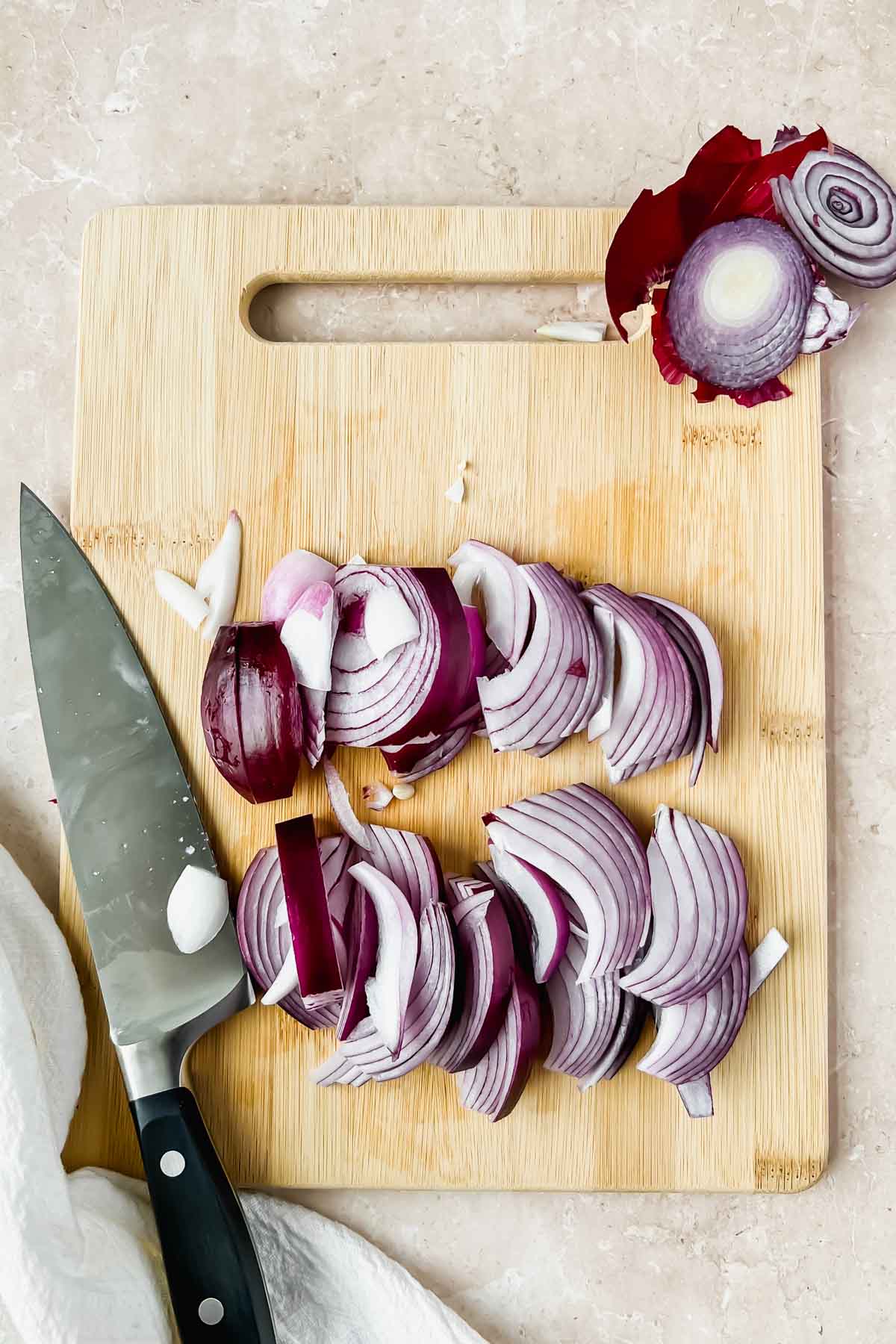 sliced red onion on wood cutting board.