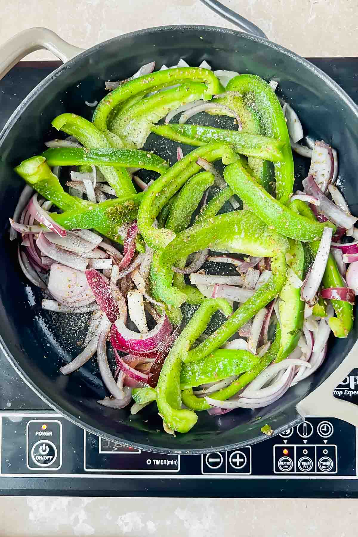 peppers and onions cooking in black skillet.