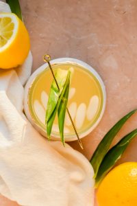 overhead shot of irish lemonade garnished with pineapple leaves on gold skewer.