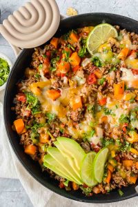 Skillet Ground Beef and Sweet Potato Recipe topped with cheese and avocado.