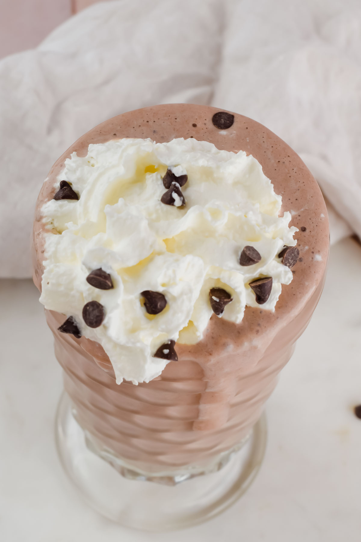 homemade wendy's frosty in milkshake glass, topped with whipped cream and chocolate chips.