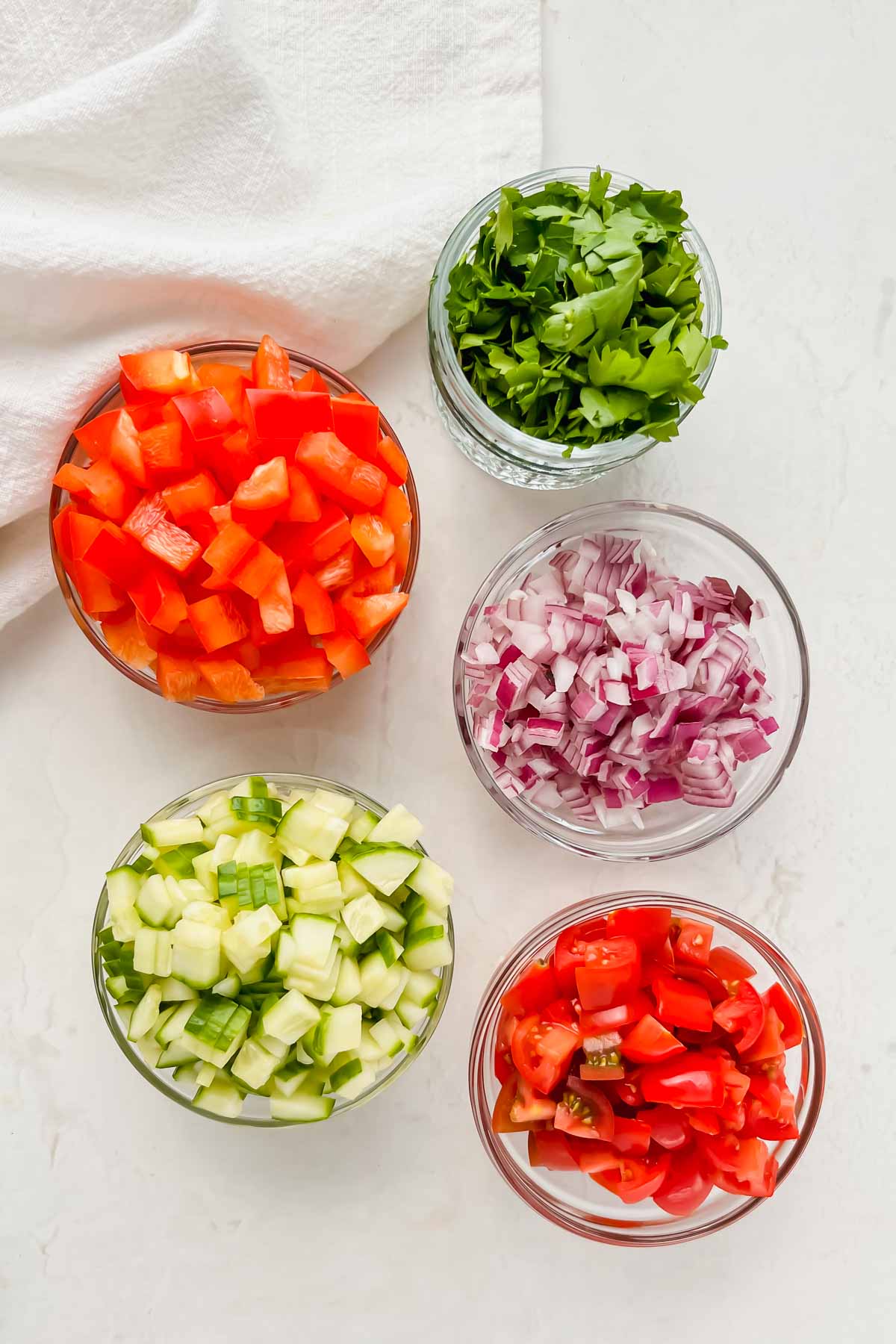 bell pepper, cucumber, onion, parsley and tomatoes chopped and separated in individual bowls.