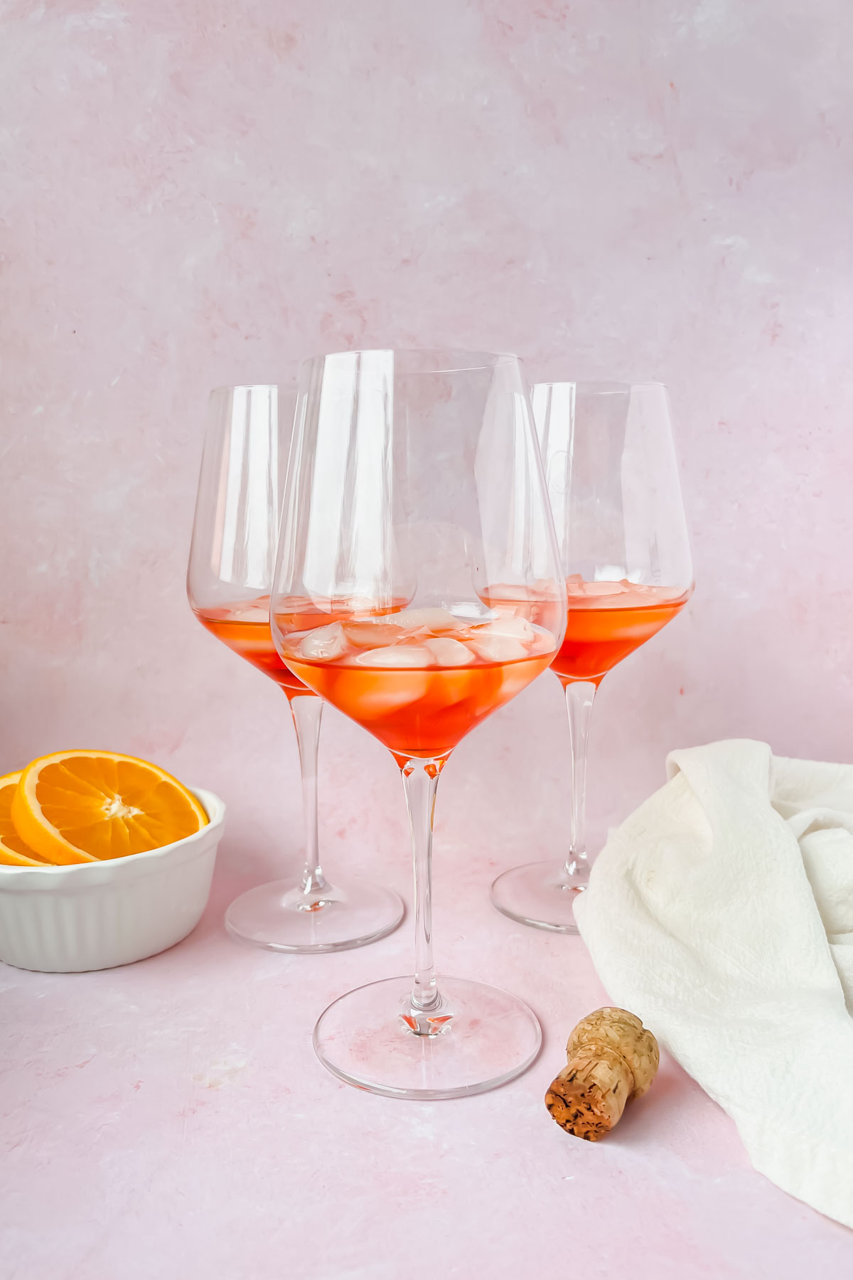 three wine glasses filled with ice and aperol.
