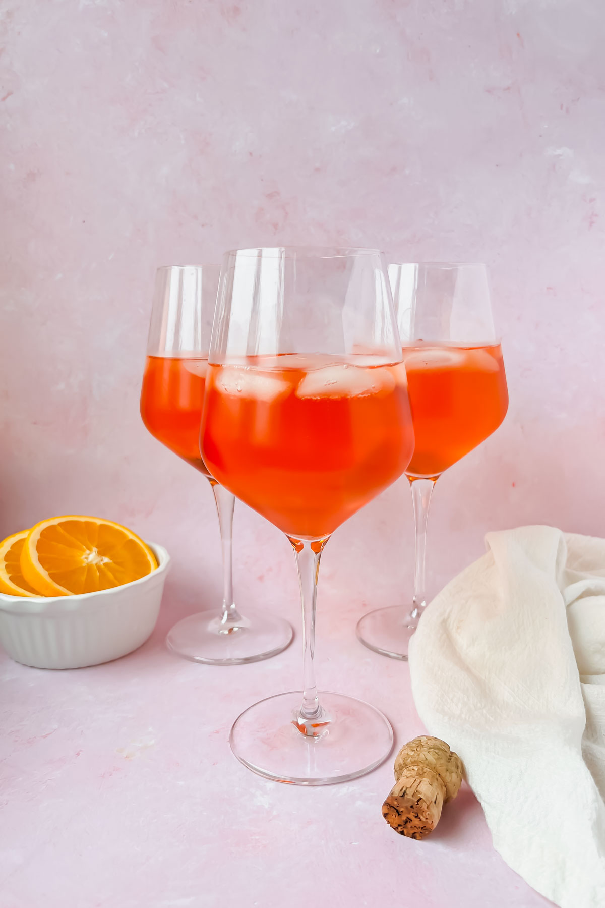 three wine glasses filled with rosé aperol spritz.