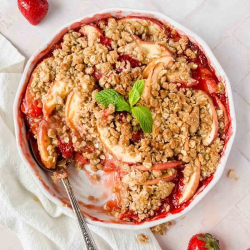 strawberry apple crisp baked to perfection with a golden crumble on top and a spoon serving it.