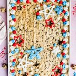 fourth of july cookie cake decorated with red, white and, blue frosting in white baking tray.