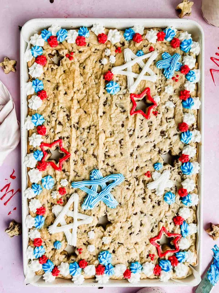 fourth of july cookie cake decorated with red, white and, blue frosting in white baking tray.