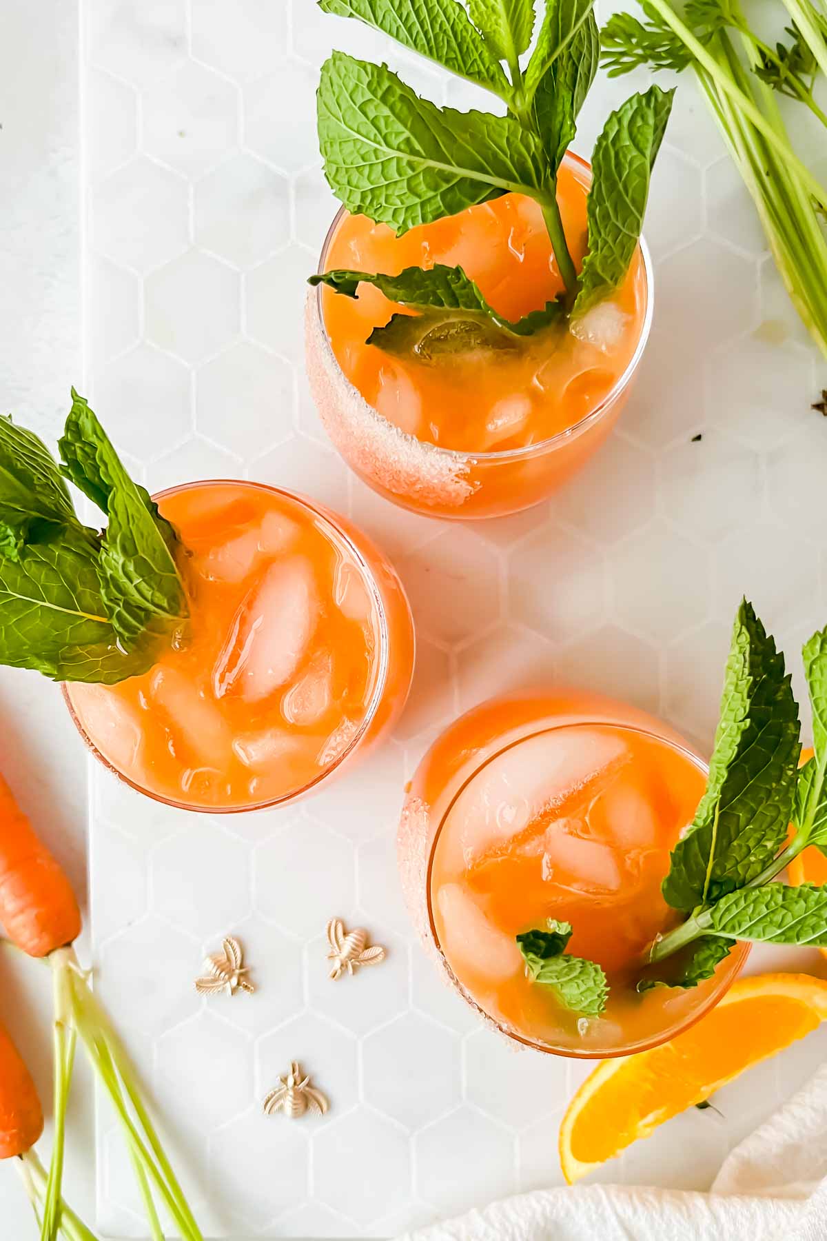 three carrot margaritas in salted cocktail glasses garnished with mint.
