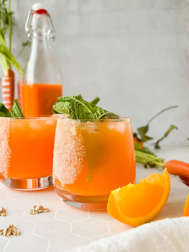 carrot margarita in salted cocktail glass garnished with mint.