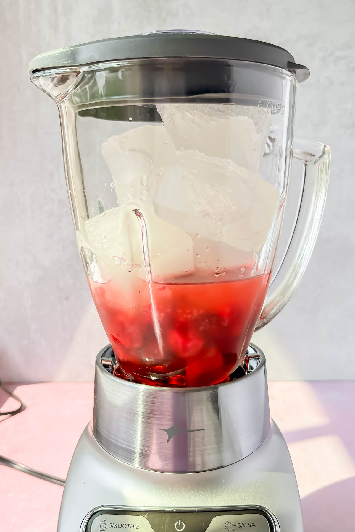 ice cubes in blender with raspberries and lemonade.
