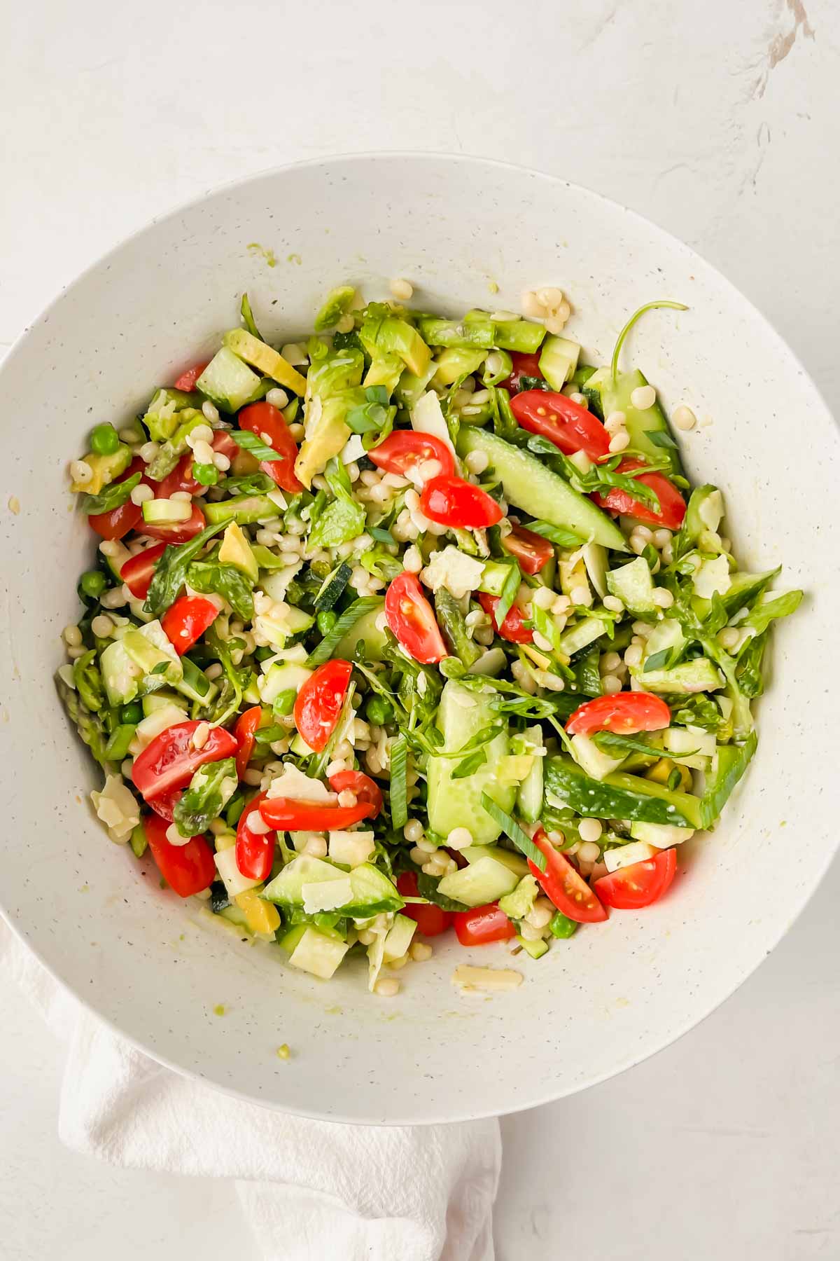 tossed green summer salad in white salad bowl.