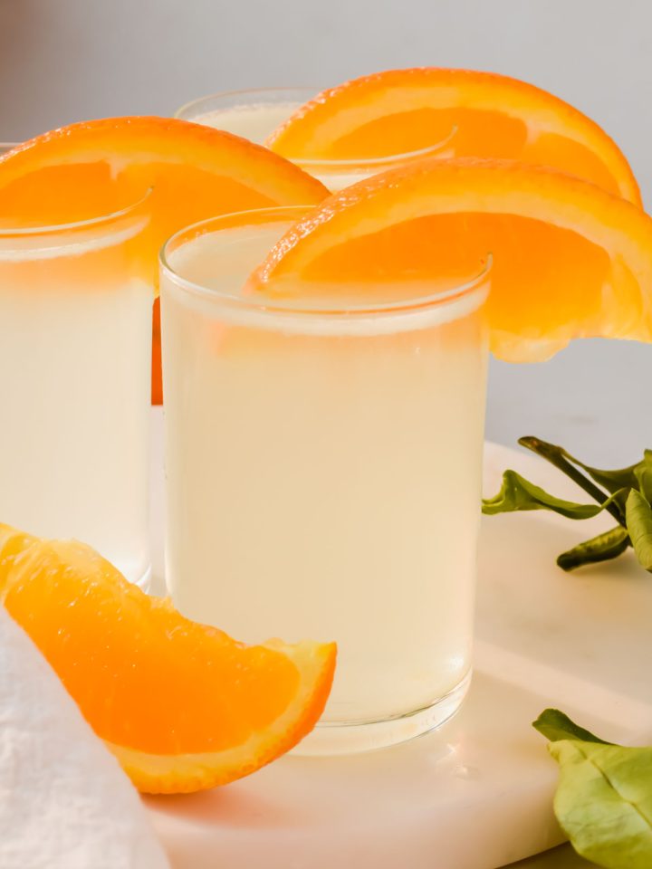 three vodka white tea shots garnished with orange wedges.