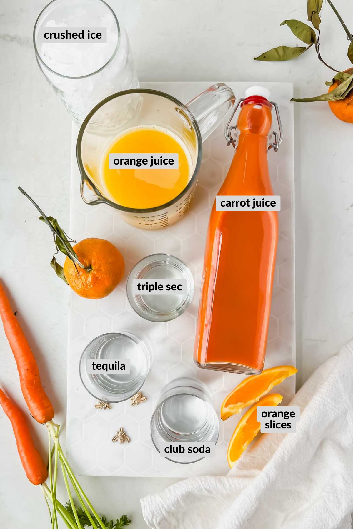 labeled carrot margarita ingredients spread on white background.