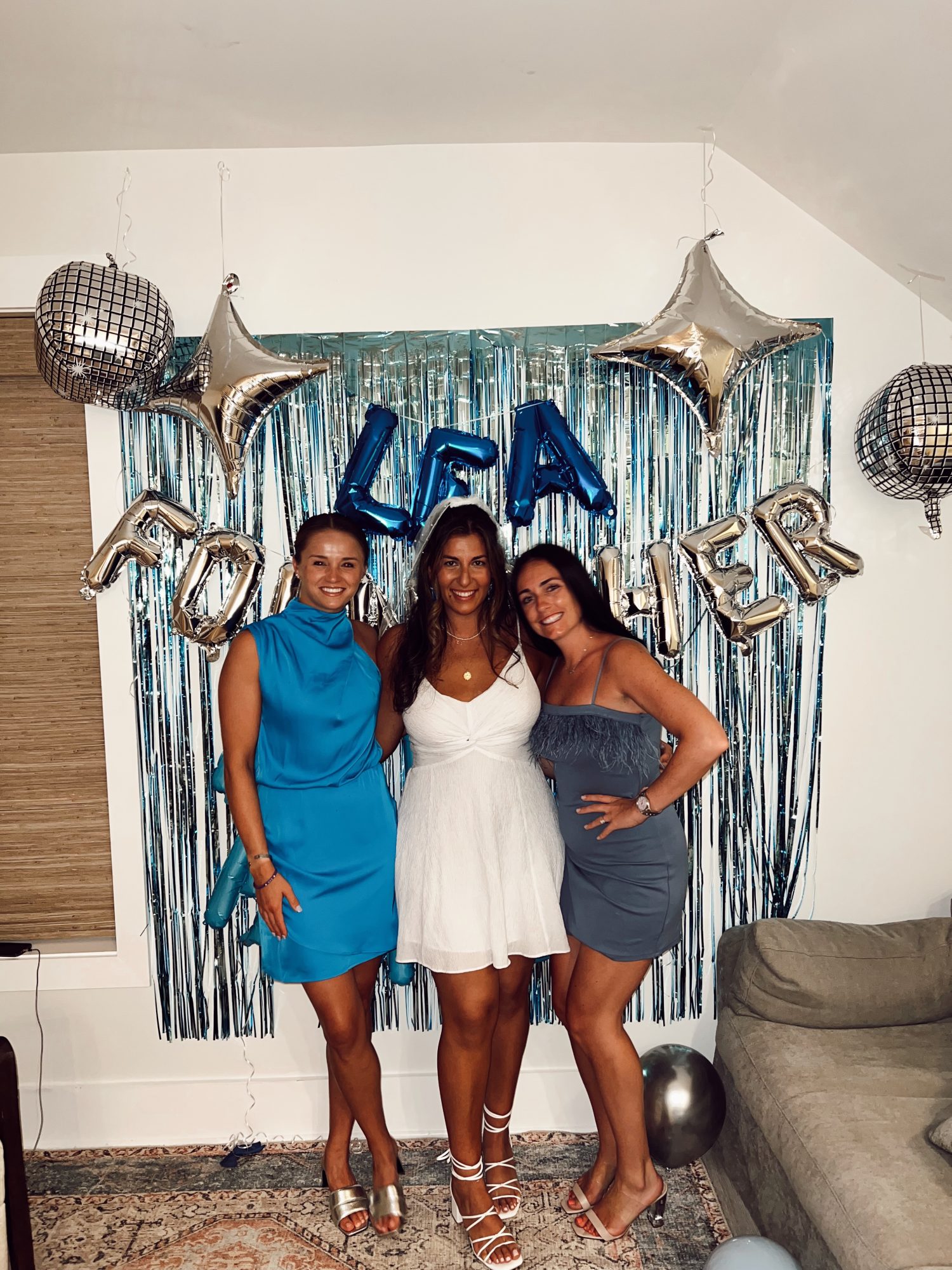 three girls in matching blue dresses with photo backdrop behind them. 
