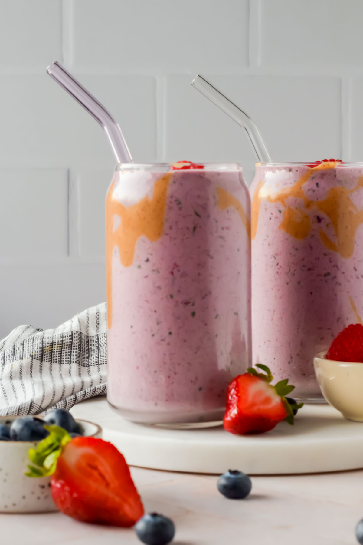 two berry smoothies in glasses smeared with peanut butter.