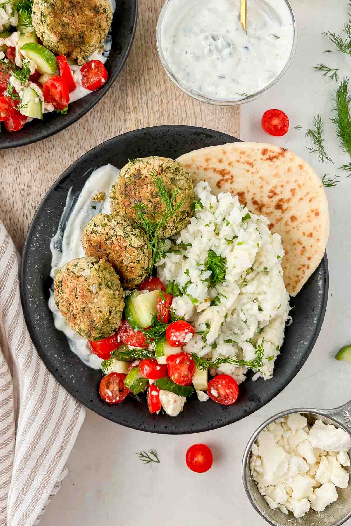 falafel rice bowl garnished with cucumber tomato salad, dill and served with pita.